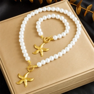 Detail of gold starfish pendant and OT clasp on white pearl necklace and bracelet set