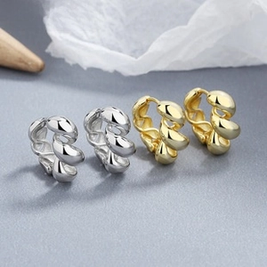 Macro view of chunky twisted 925 sterling silver hoop earrings in gold and silver finish