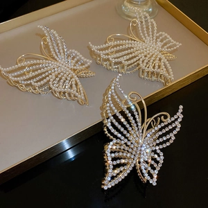 Elegant butterfly hair claws with pearls and rhinestones on a decorative tray