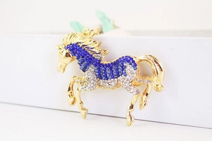 Close-up of a golden horse pendant inlaid with sparkling blue and white rhinestones