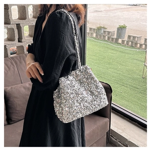 Details der silbernen Pailletten-Beuteltasche mit eleganter Metallkette am Modell