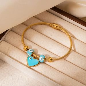 Detail of gold evil eye cable bracelet with heart pendant in jewelry display box