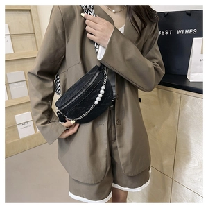 Close-up of black textured leather chest bag with pearl chain and geometric strap
