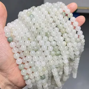 Stack of smooth pale green and white natural Tianshan jade round beads in hand
