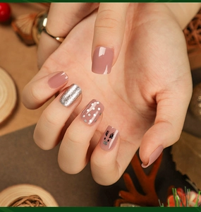 Macro shot of dusty pink press-on nails with silver glitter and reindeer festive patterns