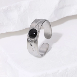 Minimalist titanium steel ring with black enamel gemstone on white stone background