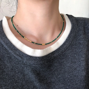 Green agate beaded necklace with gold spacers on a model over dark grey sweater