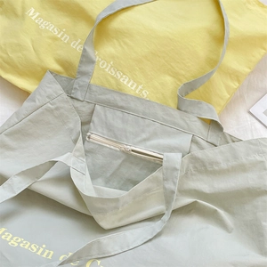 Close-up of green canvas tote bag with internal zipper pocket and croissant print