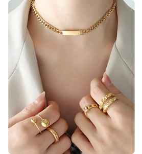 Close-up of a gold chunky chain necklace and five assorted gold rings on a model