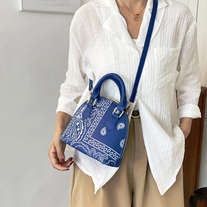 Navy blue paisley pattern shell handbag shown worn cross-body by a female fashion model