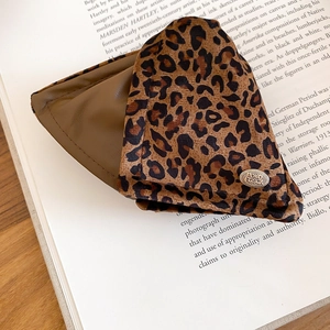 Detail of leopard print fabric pouch with brown leather accents and gold logo