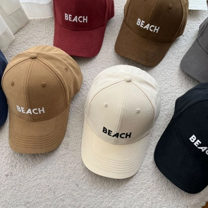 Detail of embroidered BEACH logo on multiple colors of cotton canvas baseball caps