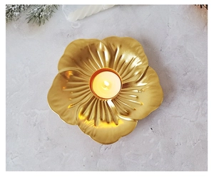 Top view of golden leaf iron candle holder with burning tea light on marble surface