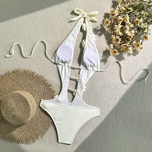 Detail of ivory cut-out swimsuit with 3D floral accents and elegant pearl button decor
