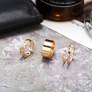 Three-piece gold hip-hop ring set with chain and wide band styles on stone background