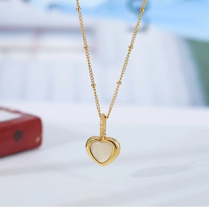 Macro shot of elegant heart pendant with white mother of pearl inlay on gold beaded chain