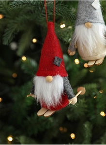 Close-up of handmade Christmas skiing gnomes hanging on a tree with warm bokeh lights