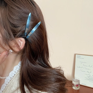 Primo piano di fermagli per capelli in acrilico blu inchiostro su capelli ricci scuri
