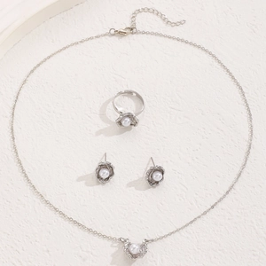 Silver jewelry set with necklace, floral pearl earrings and ring on beige texture