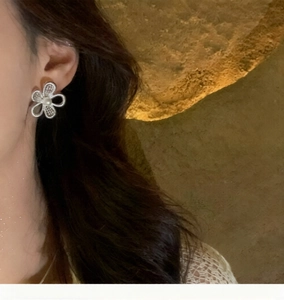 Detail shot of hollow flower earrings with white pearl center and delicate lace texture