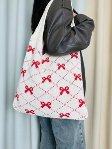 Detail of cream knitted tote bag featuring red diamond patterns and bow tie design