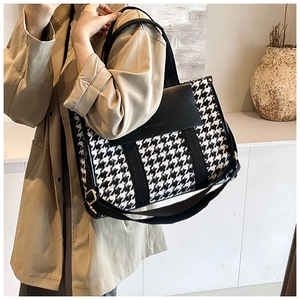 Detail of vintage houndstooth tote bag with black leather flap and wide strap