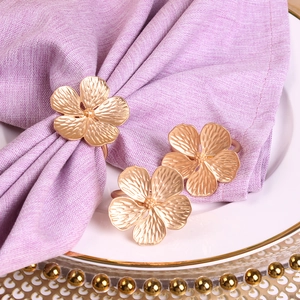 Close-up of matte gold flower napkin ring on purple cloth over decorative plate