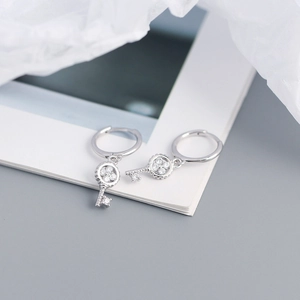 Macro detail of silver S925 clover key earrings with inlaid sparkling zircon stones