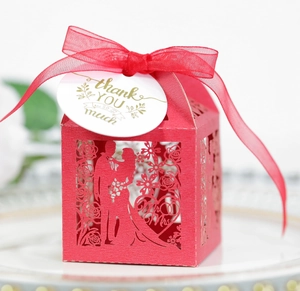 Detail of red hollowed-out wedding favor box with Mr & Mrs laser cut design and thank you tag