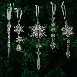 Detail of 5 clear acrylic snowflake and icicle ornaments hanging on a Christmas tree branch