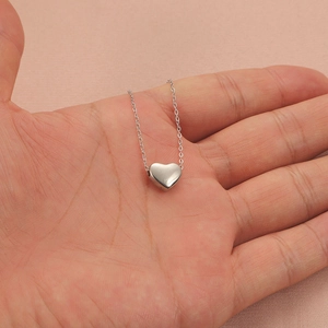 Polished silver heart pendant necklace on minimalist O-chain shown in palm