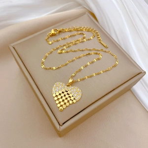 Macro shot of gold heart necklace with crystals and mesh detail on beige gift box