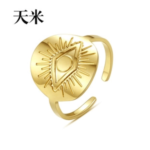 Makro-Detail eines goldenen offenen Rings mit Sonnenstrahl-Auge-Motiv auf runder Fläche