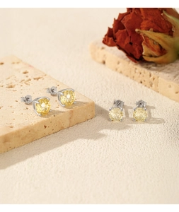 Macro shot of S925 sterling silver studs with yellow gemstones on a textured stone