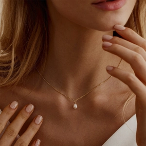 Close-up of elegant 18K gold plated necklace with freshwater pearl pendant on model