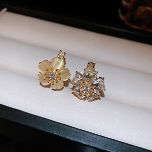 Detailed macro view of cat eye stone and rhinestone flower stud earrings in gold