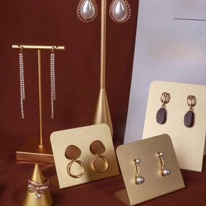 Creative metal jewelry display stand with golden pearl earrings and bow ring