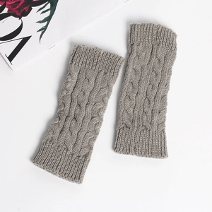 Detailed knit texture of gray cable knit fingerless gloves on a clean white background