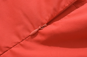 Détails macro d'une fermeture éclair invisible et du tissu sur une robe rouge