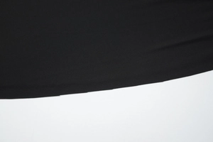 Gros plan sur la texture du tissu de la robe noire et détails des coutures de l'ourlet