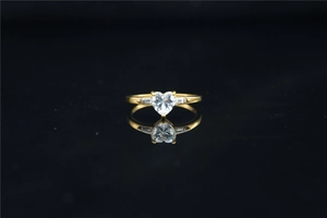 Detailed view of heart-shaped moissanite ring with side stones on reflective surface