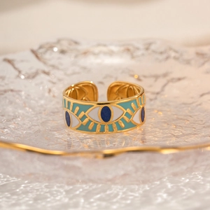Detailed macro of golden Evil Eye ring on textured glass tray with turquoise enamel