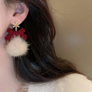 Detail of winter festive earrings with snowflake studs red bows and white plush balls