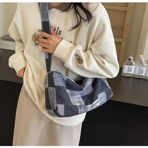 Détail d'un sac bandoulière en patchwork de denim bleu avec un sweat blanc décontracté