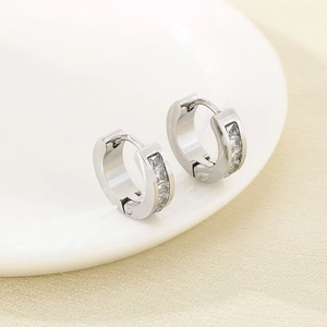Gros plan de boucles d'oreilles rondes en argent avec zircone sur une assiette blanche