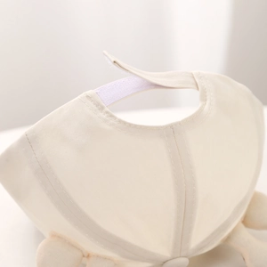 Détail de la sangle Velcro réglable et du tissu en coton doux de la casquette bébé