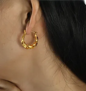 Gros plan détaillé d'une boucle d'oreille créole torsadée plaquée or 18 carats