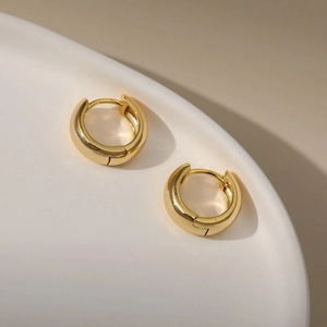 Minimalist 18K gold plated thick hoop earrings on a white ceramic display plate