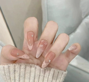 Detail of French plaid bow press-on nails with pink gradient and rhinestone accents