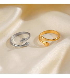 Macro detail of gold and silver hugging hands open rings on beige silk fabric